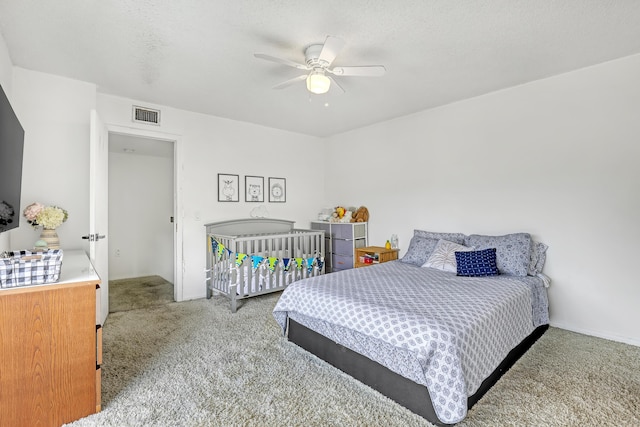 bedroom with a ceiling fan, light colored carpet, visible vents, and a textured ceiling