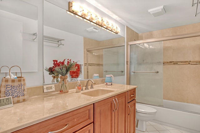 bathroom featuring vanity, combined bath / shower with glass door, tile patterned flooring, and toilet