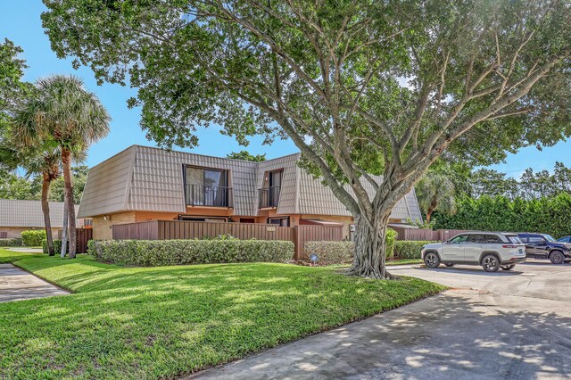 view of front of home with a balcony and a front yard