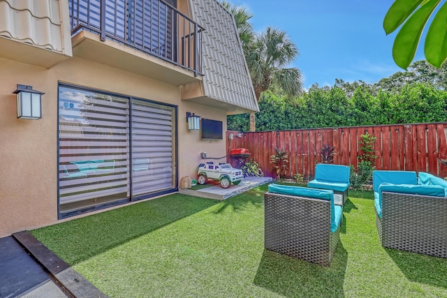 view of yard with an outdoor living space, fence, and a balcony