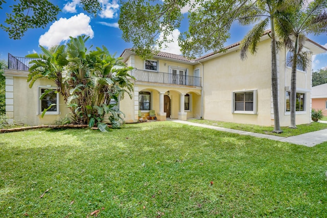 mediterranean / spanish home featuring a front lawn and a balcony