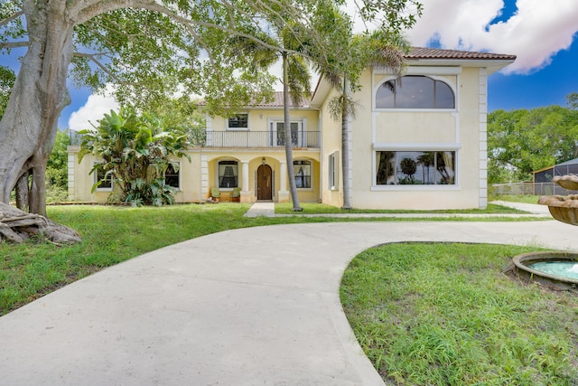 mediterranean / spanish-style house featuring a balcony and a front lawn