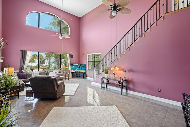 tiled living room featuring ceiling fan, a high ceiling, and a healthy amount of sunlight