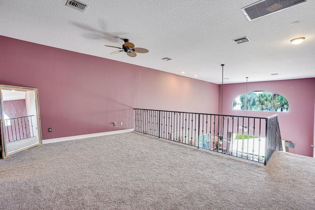 carpeted spare room with a textured ceiling and ceiling fan