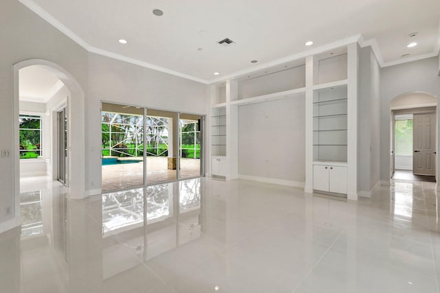 tiled empty room featuring a healthy amount of sunlight, built in features, and crown molding