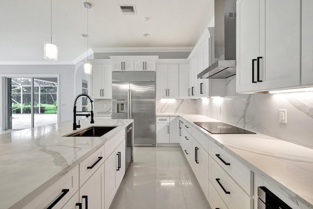 kitchen with sink, hanging light fixtures, stainless steel appliances, wall chimney range hood, and white cabinets