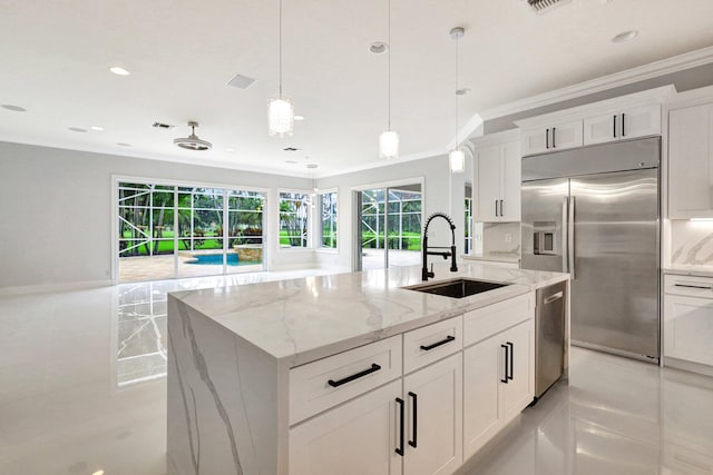 kitchen featuring light stone countertops, sink, stainless steel appliances, a kitchen island with sink, and white cabinets