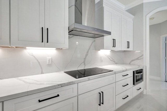 kitchen with white cabinetry, light stone counters, wall chimney exhaust hood, and black electric cooktop