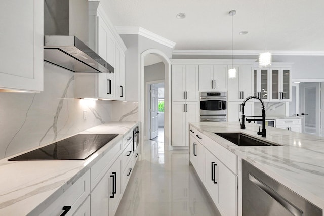 kitchen featuring appliances with stainless steel finishes, wall chimney exhaust hood, sink, white cabinetry, and hanging light fixtures