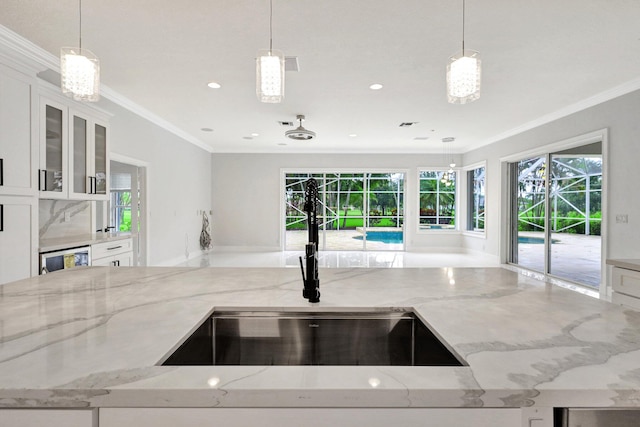 kitchen with light stone countertops, sink, and hanging light fixtures