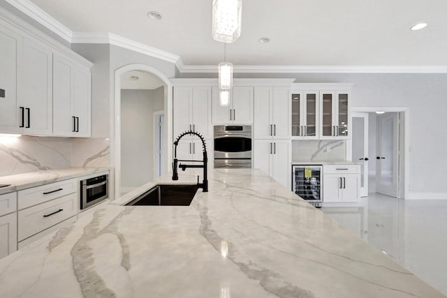 kitchen featuring pendant lighting, white cabinets, wine cooler, double oven, and light stone counters