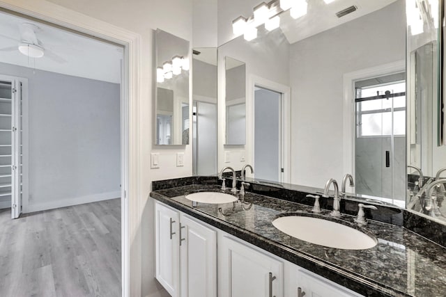 bathroom with hardwood / wood-style flooring, ceiling fan, walk in shower, and vanity