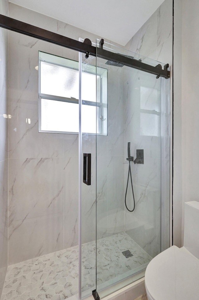 bathroom featuring toilet and a shower with door