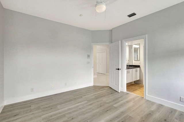 unfurnished bedroom featuring ceiling fan, sink, connected bathroom, and light hardwood / wood-style flooring