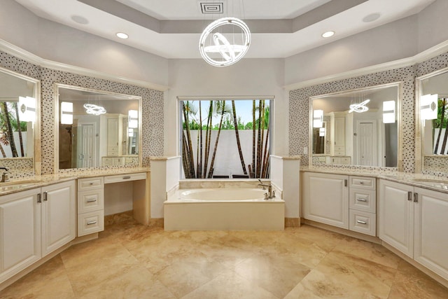 bathroom featuring a raised ceiling, a tub, vanity, and a chandelier