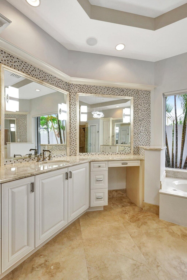 bathroom featuring a washtub, decorative backsplash, vanity, and a raised ceiling