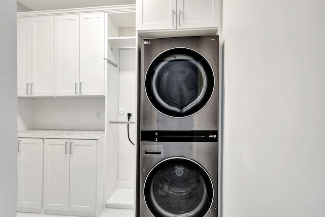 laundry area featuring cabinets and stacked washer and clothes dryer