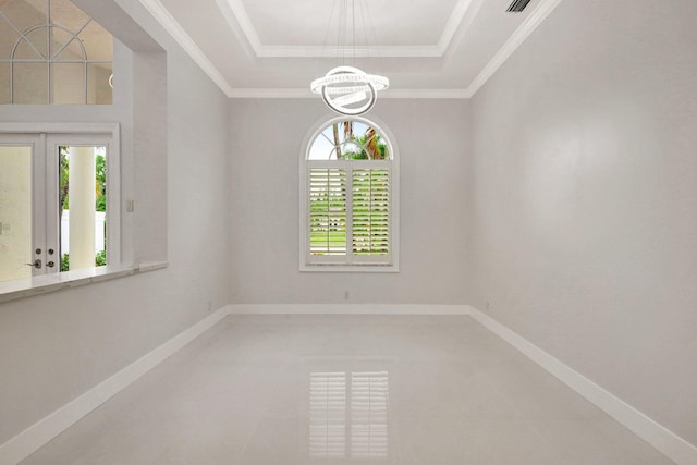 empty room with a tray ceiling, ornamental molding, a healthy amount of sunlight, and a notable chandelier