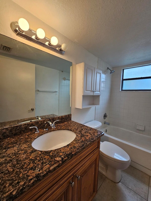 full bathroom featuring vanity, tile patterned flooring, a textured ceiling, tiled shower / bath, and toilet