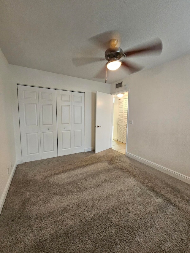 unfurnished bedroom with light colored carpet, a closet, a textured ceiling, and ceiling fan