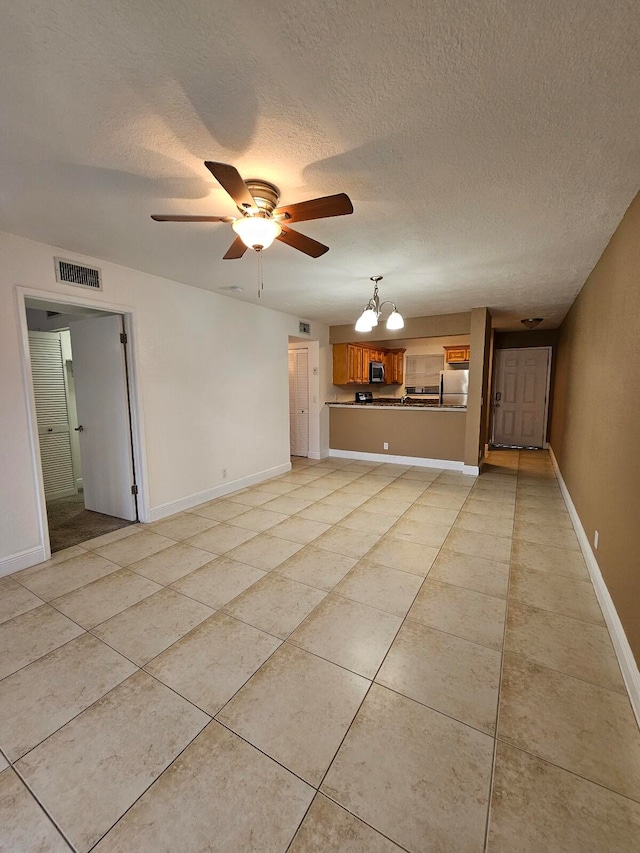 unfurnished living room with a textured ceiling, light tile patterned flooring, and ceiling fan with notable chandelier