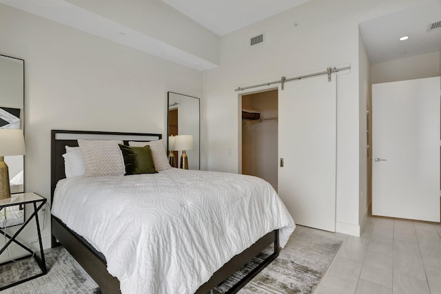 bedroom with a walk in closet, a barn door, a closet, and light tile patterned floors