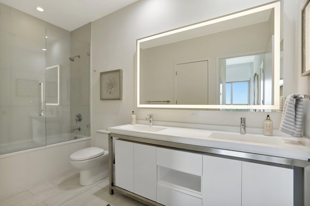 full bathroom with tile patterned floors, double sink vanity, shower / bath combination with glass door, and toilet