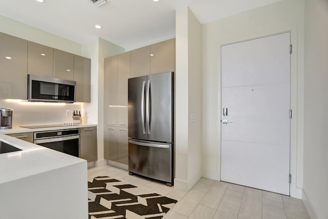 kitchen featuring appliances with stainless steel finishes, light tile patterned flooring, and gray cabinetry