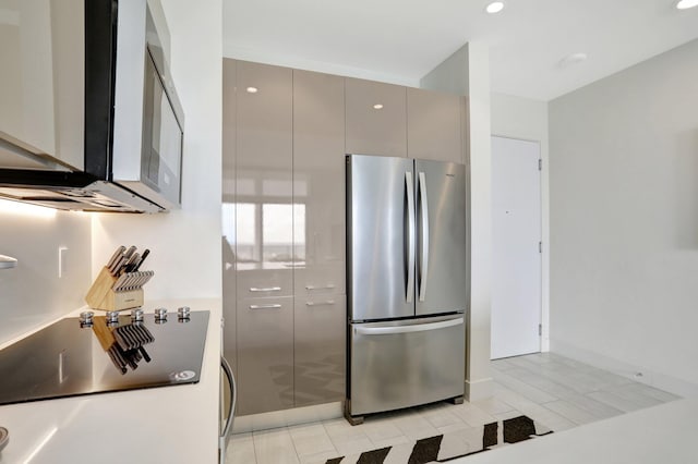 kitchen with light tile patterned floors, range, stainless steel refrigerator, and gray cabinets