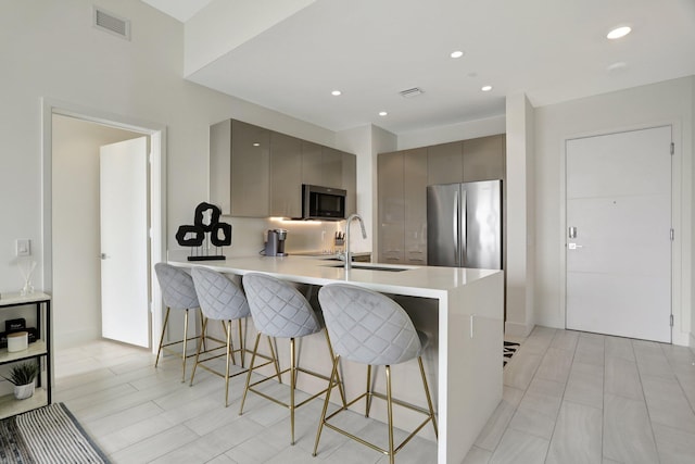 kitchen with a kitchen breakfast bar, gray cabinets, sink, kitchen peninsula, and stainless steel appliances