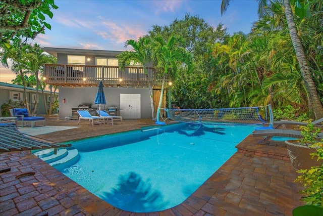 pool at dusk featuring a patio area