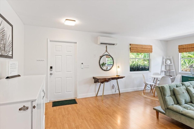 foyer with a wall mounted air conditioner and light hardwood / wood-style floors