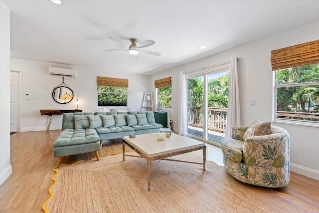 living room featuring a wall mounted air conditioner, ceiling fan, and light hardwood / wood-style floors