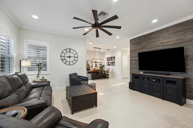 tiled living room with ceiling fan with notable chandelier and ornamental molding