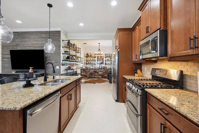 kitchen featuring pendant lighting, a center island with sink, sink, light stone countertops, and appliances with stainless steel finishes