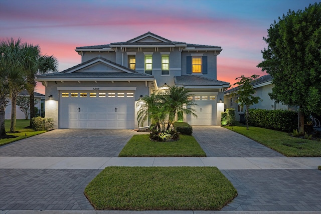 front of property with a garage and a lawn