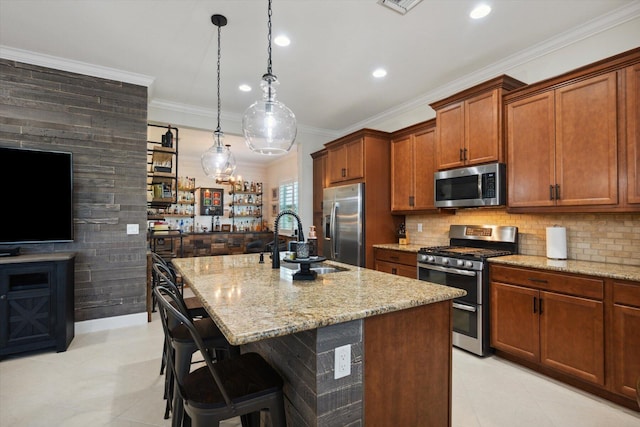 kitchen with a breakfast bar, crown molding, a center island with sink, and stainless steel appliances