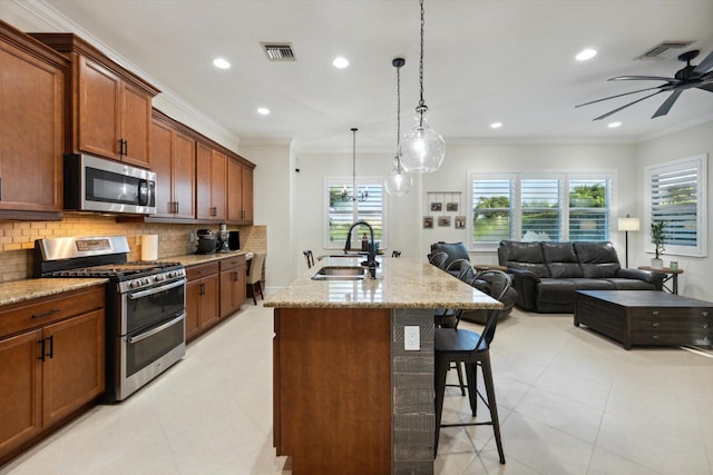 kitchen featuring sink, stainless steel appliances, decorative backsplash, a kitchen island with sink, and a breakfast bar