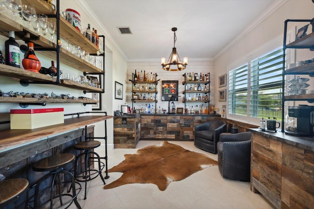 bar with a notable chandelier, light tile patterned flooring, and ornamental molding