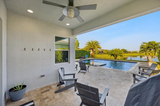 view of swimming pool featuring a patio area, ceiling fan, and a water view