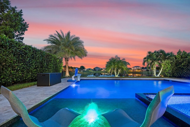 pool at dusk featuring a patio area and a jacuzzi