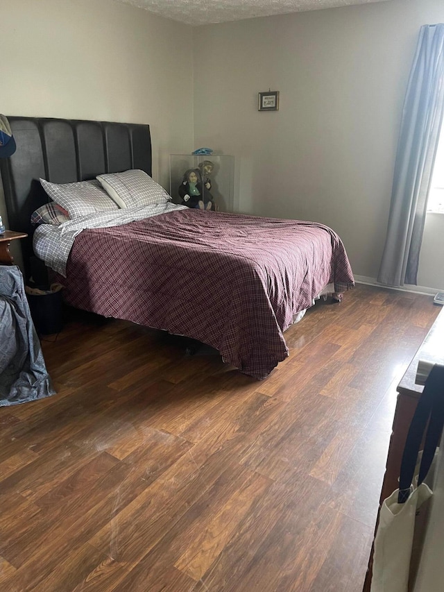 bedroom featuring a textured ceiling and dark hardwood / wood-style flooring