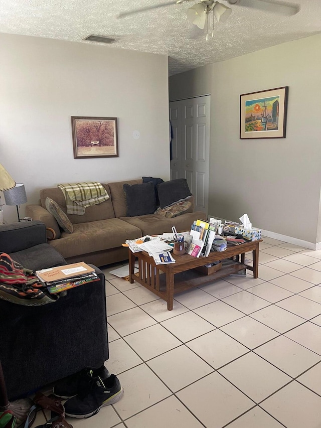 living room featuring ceiling fan, light tile patterned floors, and a textured ceiling