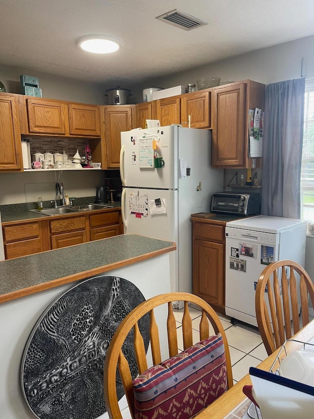 kitchen featuring a textured ceiling, white fridge, sink, and light tile patterned floors