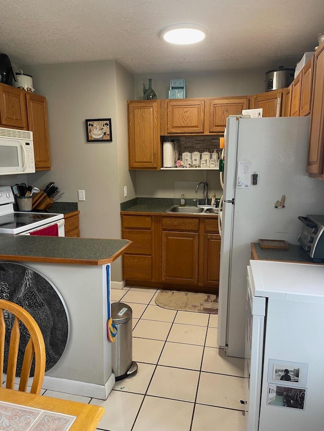 kitchen featuring white appliances, light tile patterned flooring, a textured ceiling, and sink