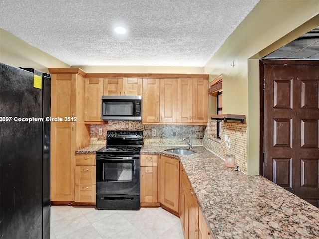 kitchen with sink, light stone counters, black appliances, and tasteful backsplash