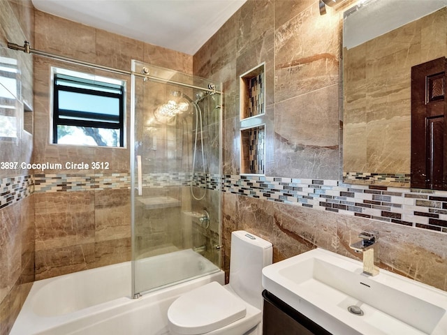 full bathroom featuring backsplash, combined bath / shower with glass door, vanity, tile walls, and toilet