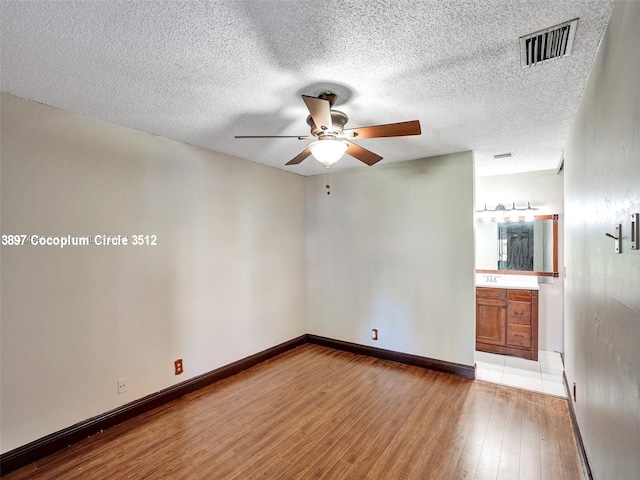 empty room featuring hardwood / wood-style flooring, a textured ceiling, sink, and ceiling fan