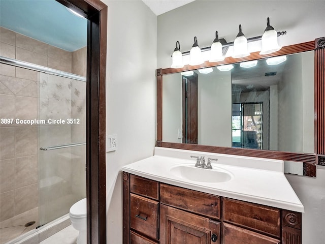 bathroom featuring a shower with door, toilet, and vanity