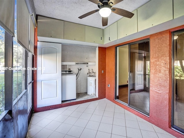 unfurnished sunroom featuring ceiling fan, a wealth of natural light, washer / dryer, and electric water heater